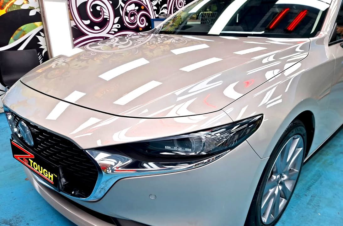 Silver bonnet and grille of the Mazda 3 reflecting the ceiling lights.