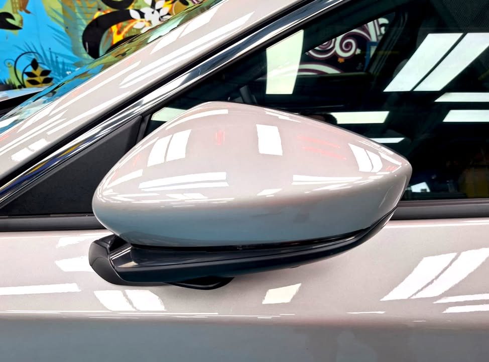 Silver side mirror cap with reflections of the workshop lights.