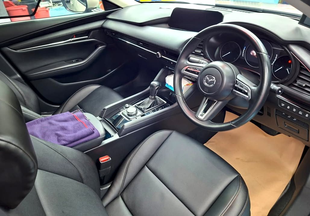 Mazda 3 interior with black leather seats and steering wheel.