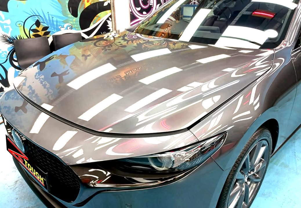Front of the Mazda 3 with sharp reflections in the bonnet and a ZeTough plate on the bumper.