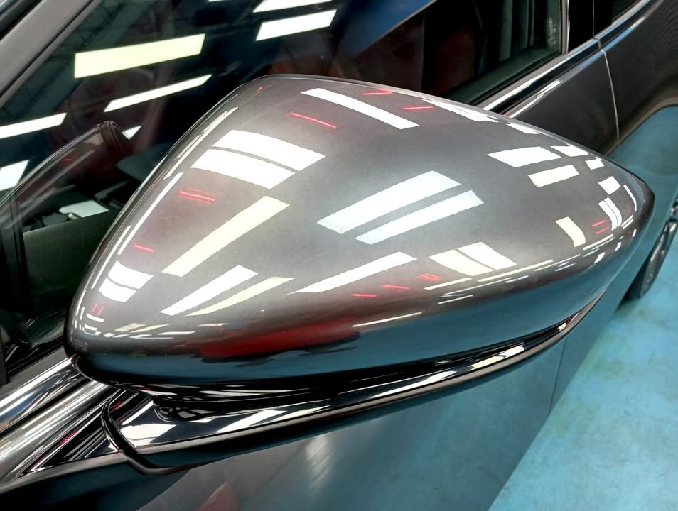 Grey side mirror cap reflecting the workshop ceiling lights.