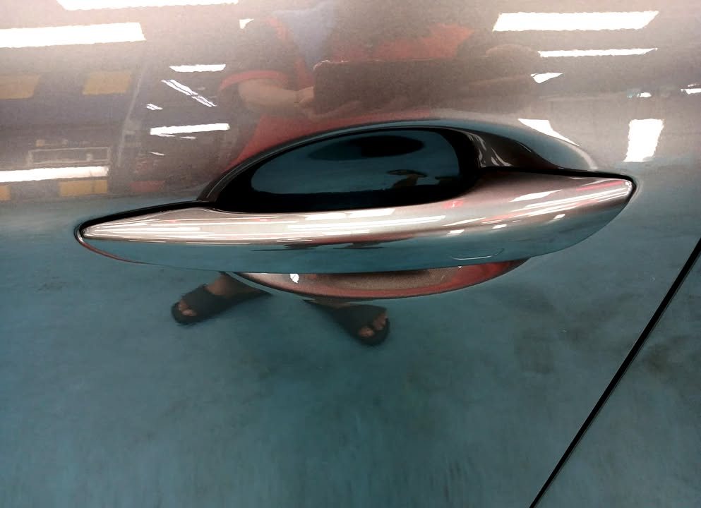 Door handle on the grey door panel with reflections in the paint.