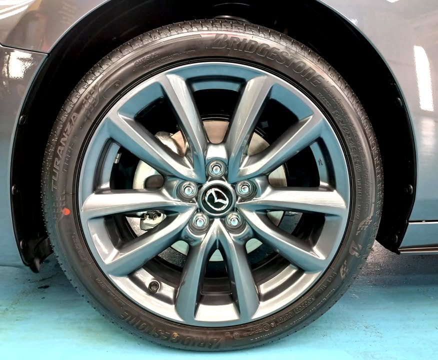 Clean grey multi-spoke alloy wheel with Mazda centre cap.