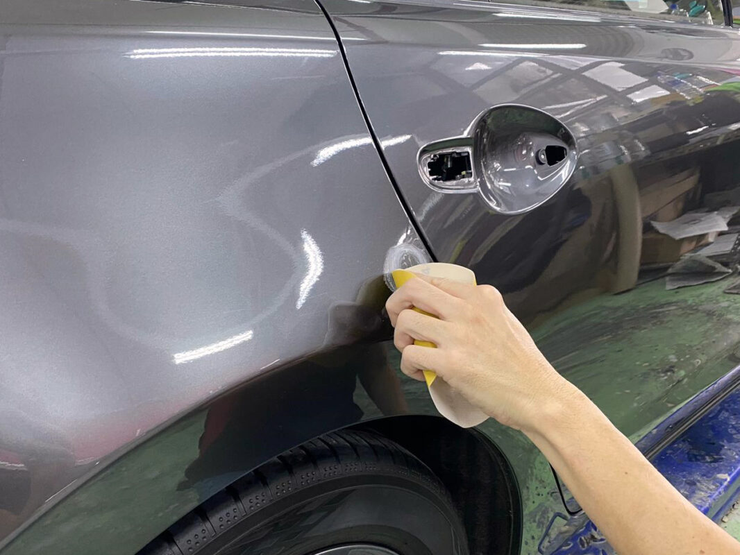A technician examining the Mazda 6 surface for scratches and dents on day three.