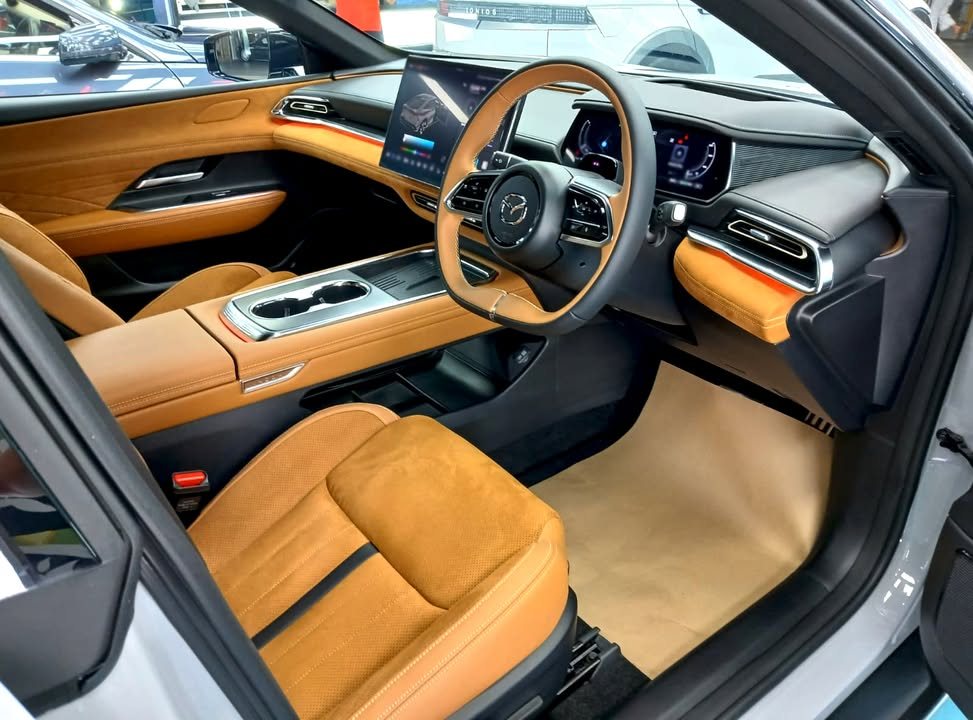 Interior of the Mazda 6e with tan leather seats, steering wheel and centre console.