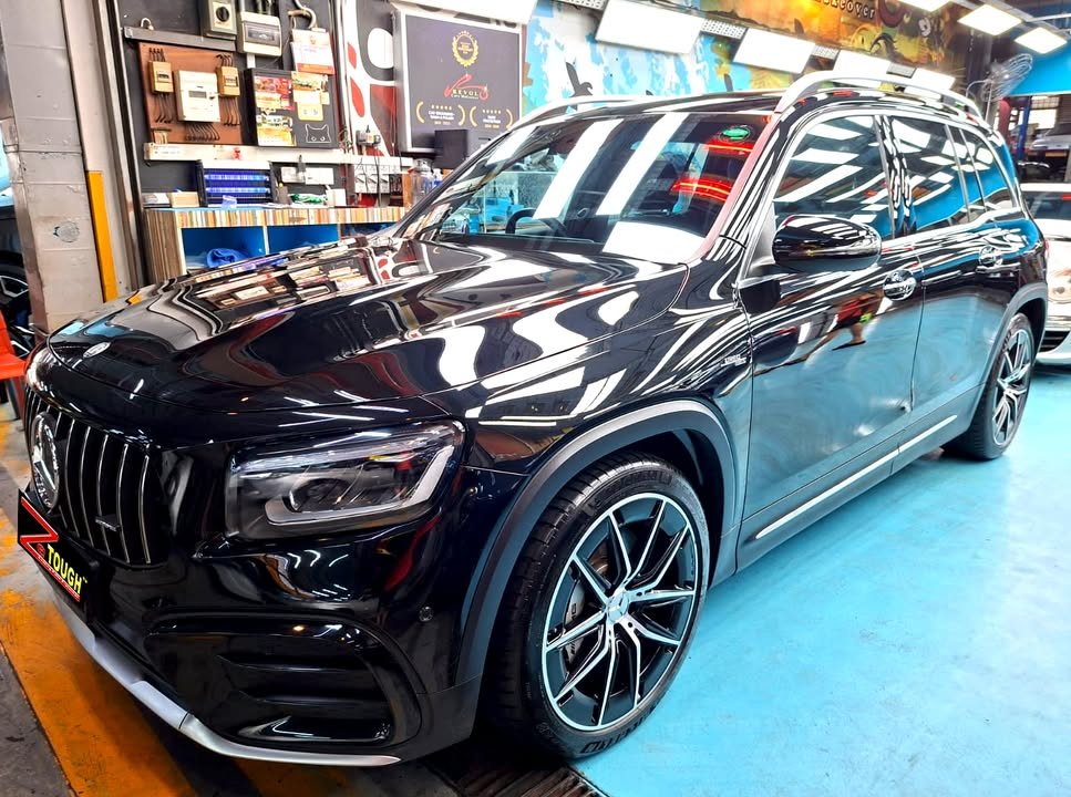 Black Mercedes-AMG GLB 35, front three-quarter view, in the AMK Autopoint workshop after coating.