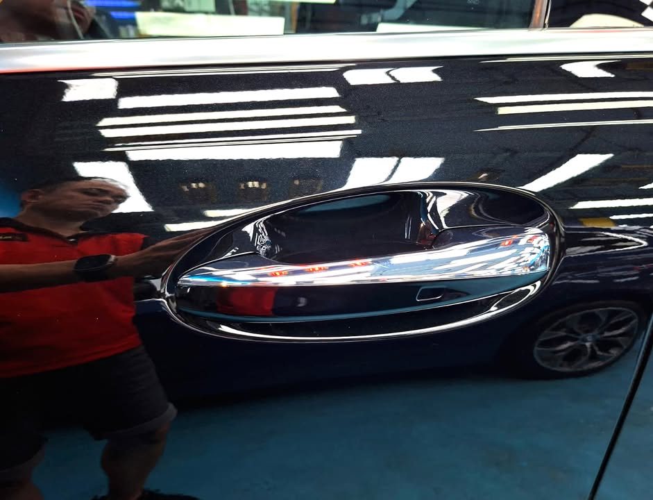 Chrome door handle on the black door panel with a deep reflection.