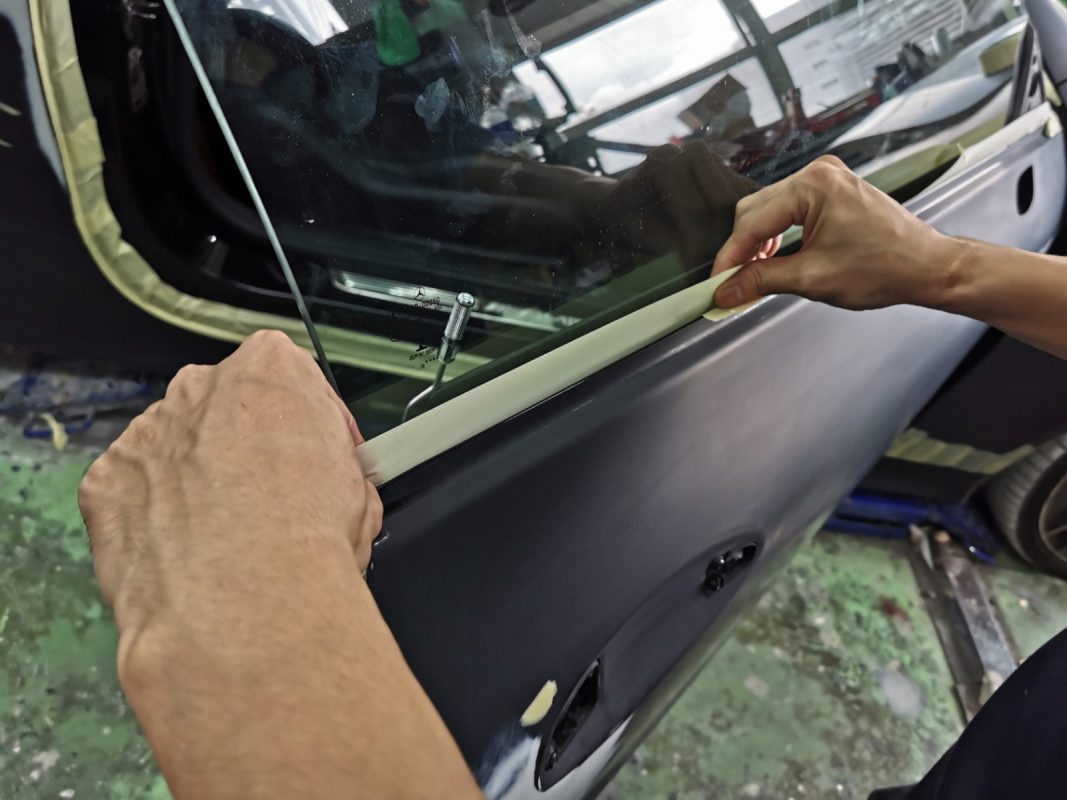Non-painted surfaces being masked off on the AMG E53 before spraying.