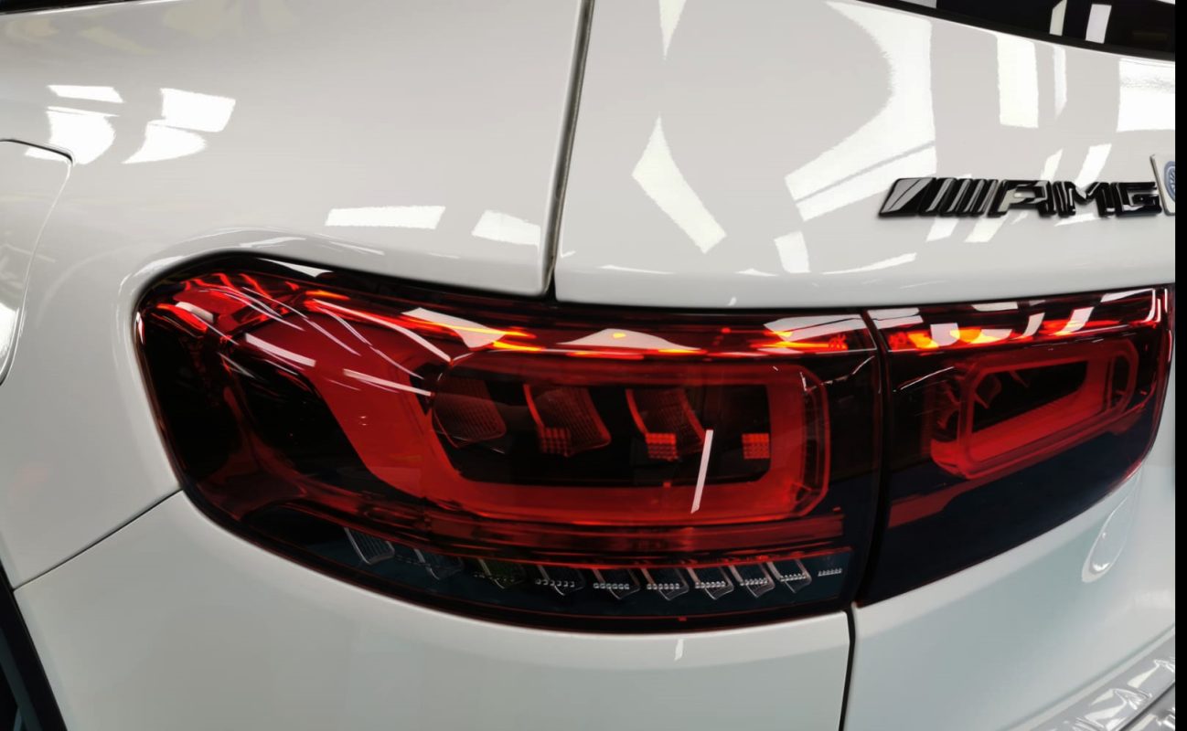The coated bonnet of the Mercedes-Benz AMG GLB35 under workshop lighting.