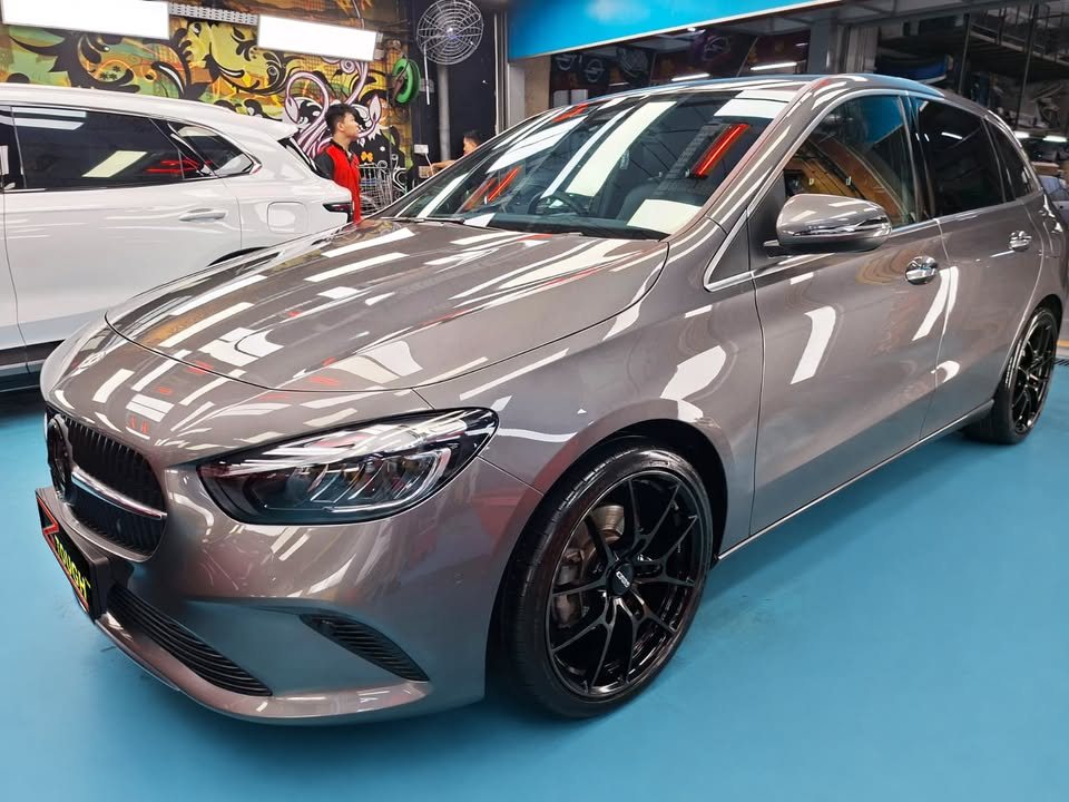 Front three-quarter view of a grey Mercedes-Benz B 180 with black wheels in the Revol Carz Makeover studio.