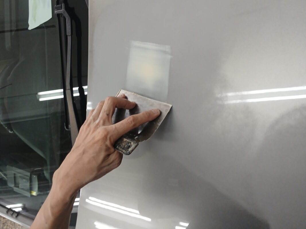 A technician inspecting the C180 surface for scratches and dents before sanding.