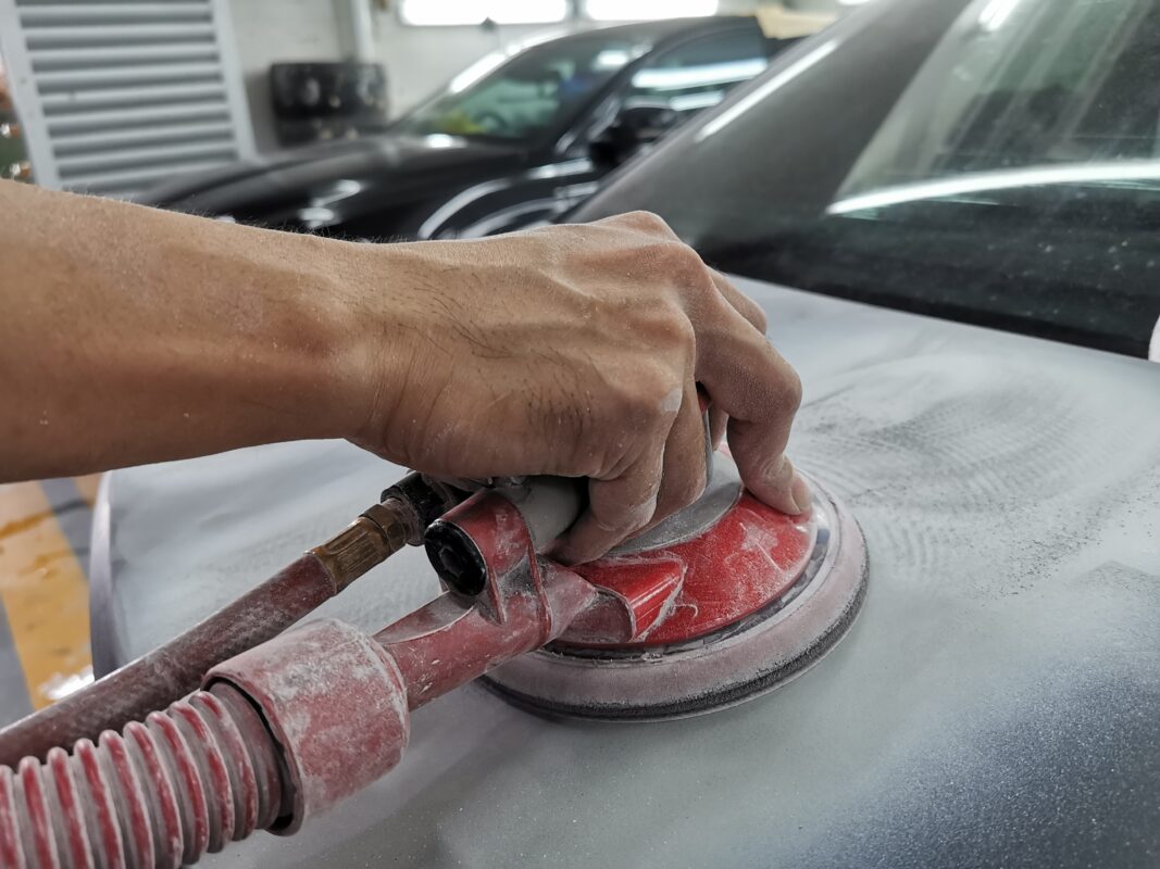 A Revol Carz technician inspecting and patching surface imperfections on the C180's body.