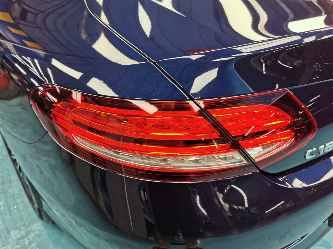 The coated bonnet of the Mercedes-Benz C180 under workshop lighting.