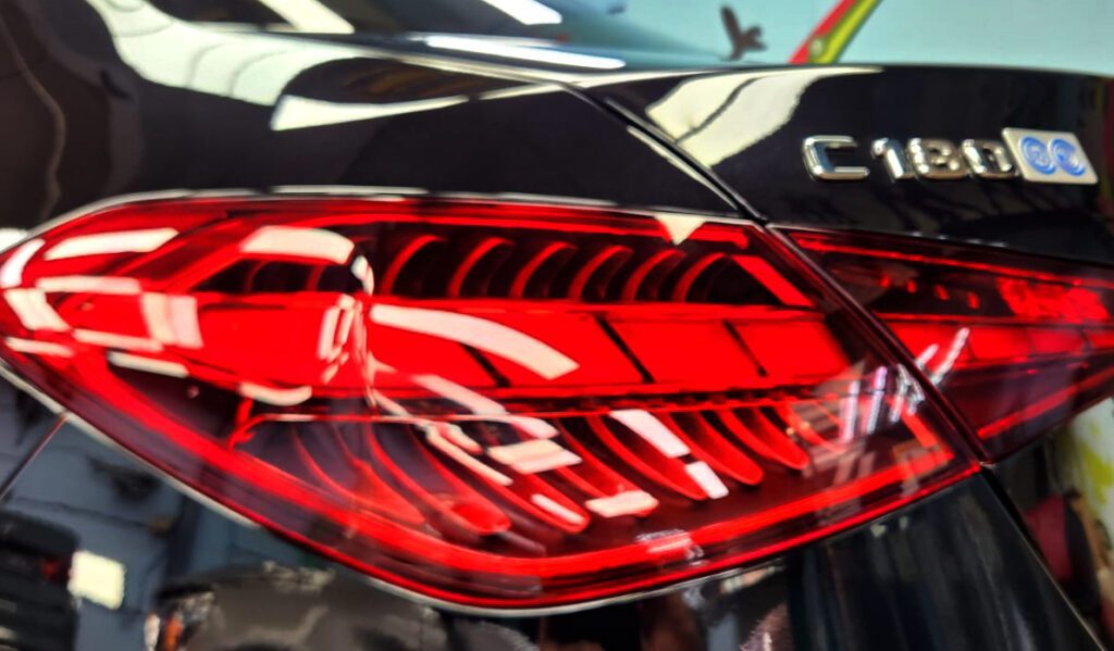 The coated bonnet of the Mercedes-Benz C180 under workshop lighting.