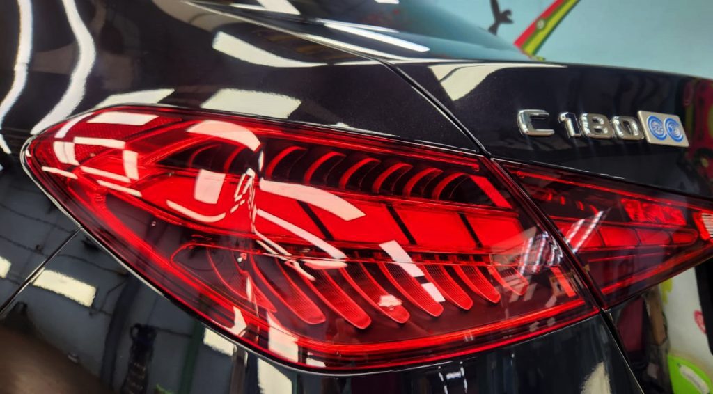 The coated bonnet of the Mercedes-Benz C180 under workshop lighting.