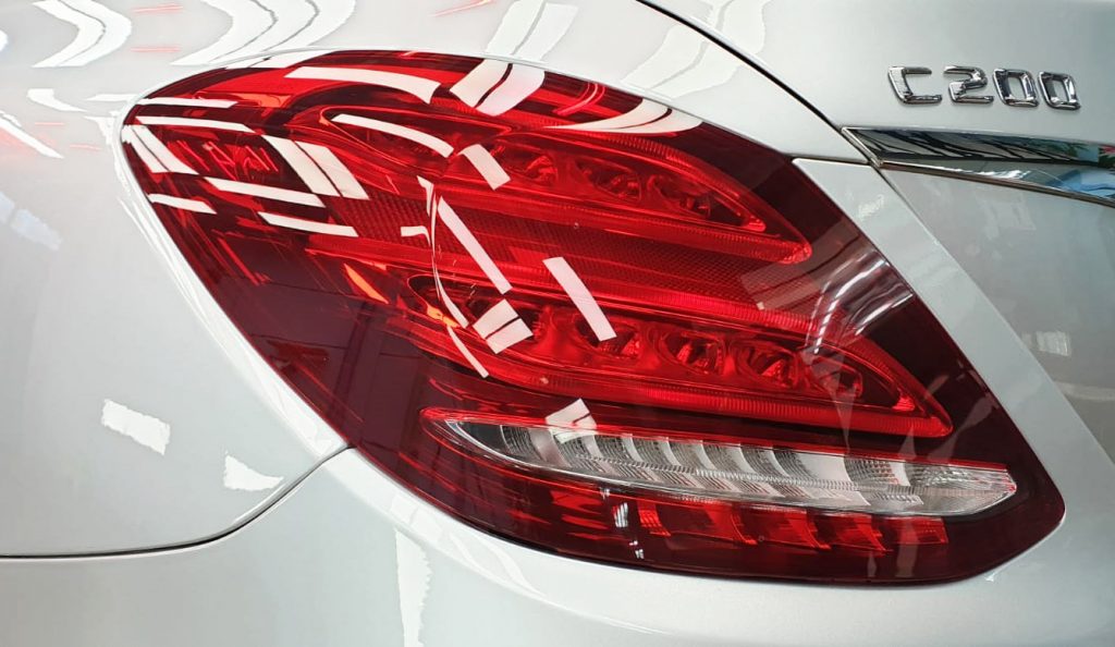The coated bonnet of the Mercedes-Benz C200 under workshop lighting.