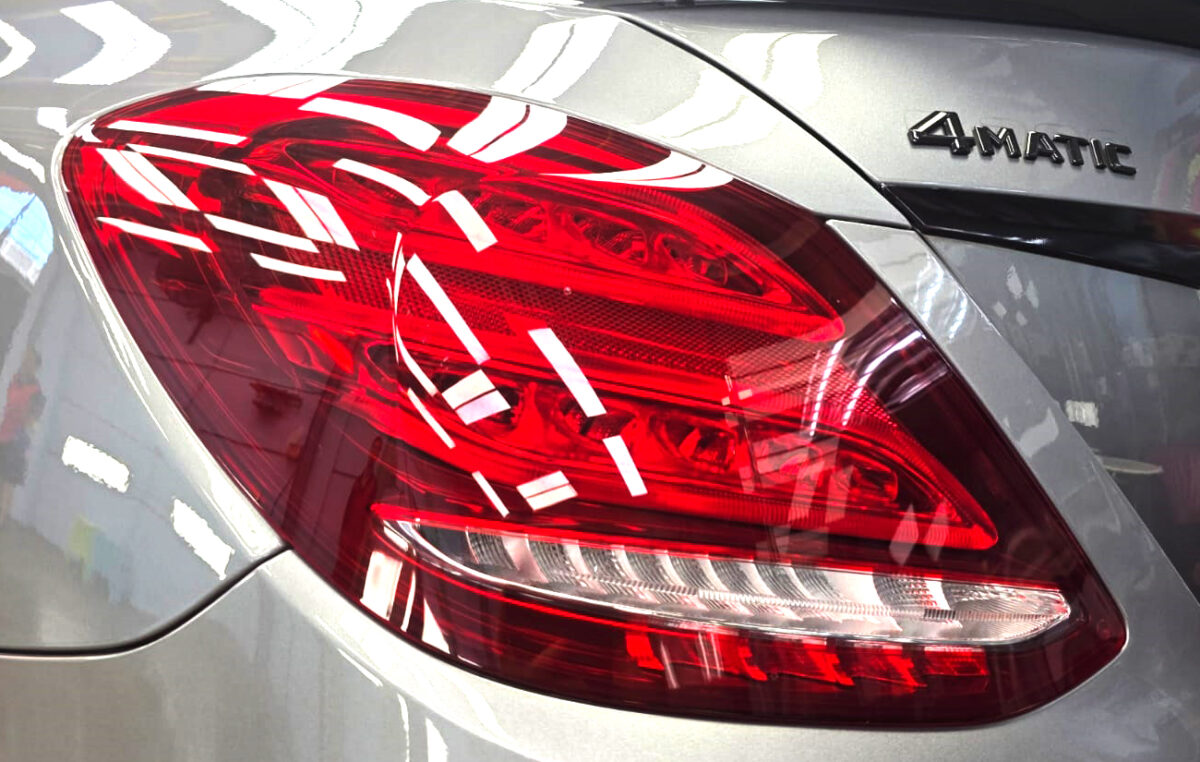 The coated bonnet of the Mercedes-Benz C200 under workshop lighting.