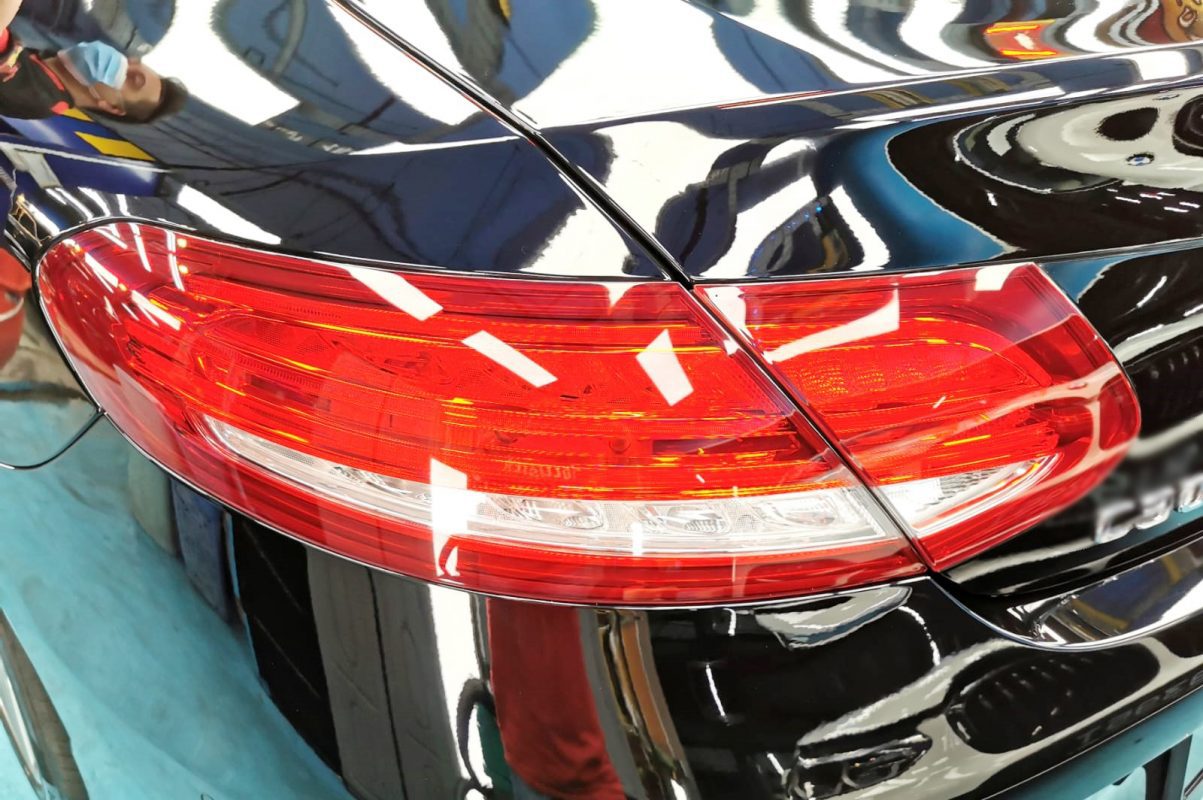 The coated bonnet of the black Mercedes-Benz C300 under workshop lighting.