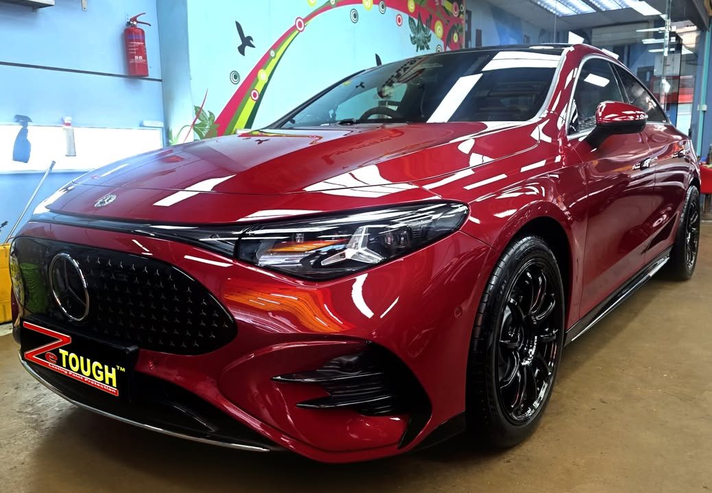 Red Mercedes-Benz CLA 250+, front three-quarter view, with ceiling lights reflected on the bonnet after its ZeTough Titanium coating.