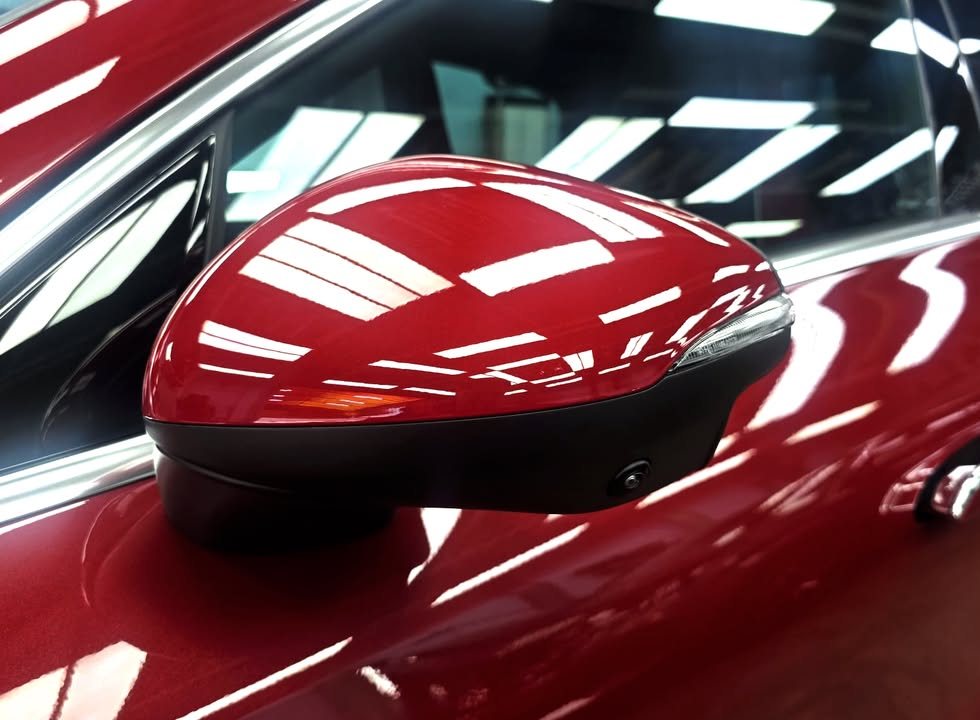 Red side mirror cap with sharp reflections of the ceiling lights.