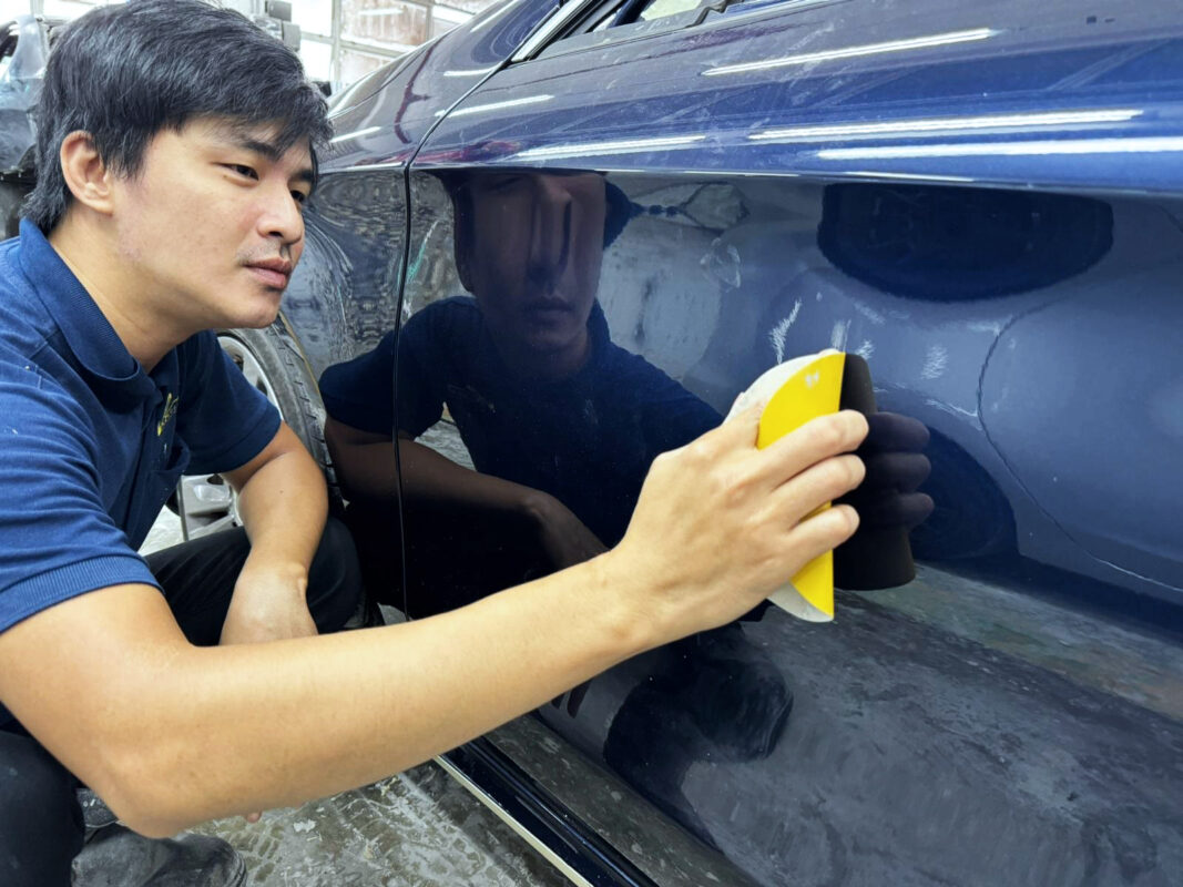 Revol Carz technician examining the CLA200 surface for scratches and dents.