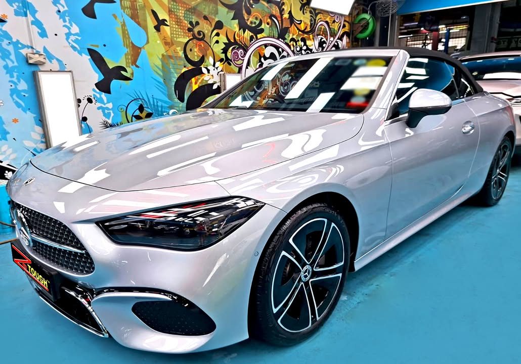Silver Mercedes-Benz CLE 180 Cabriolet with the roof down, front three-quarter view in the workshop.