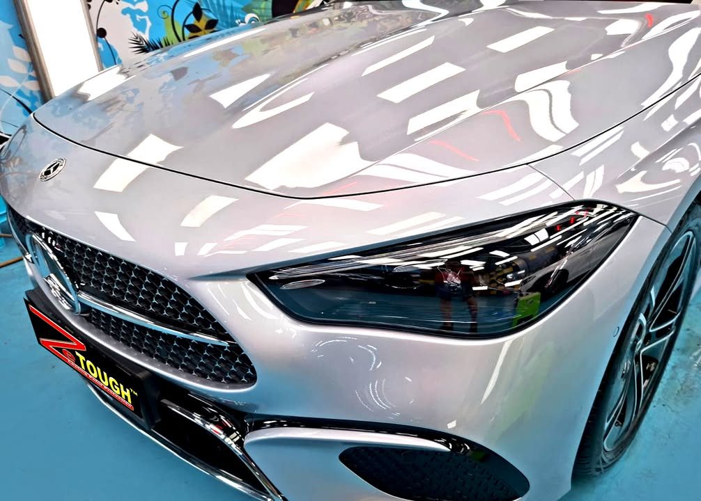 Front of the silver CLE showing the star-pattern grille and headlight, with a ZeTough plate on the bumper.
