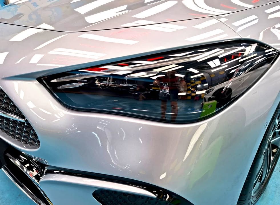 Close-up of the headlight with ceiling lights reflected in the silver wing.