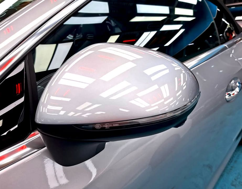 Silver side mirror cap reflecting the workshop ceiling lights.