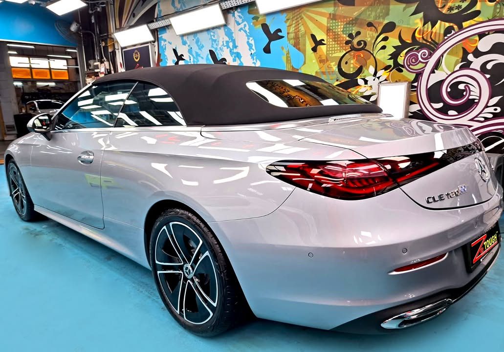 Rear three-quarter view of the CLE 180 Cabriolet with the black soft top up.