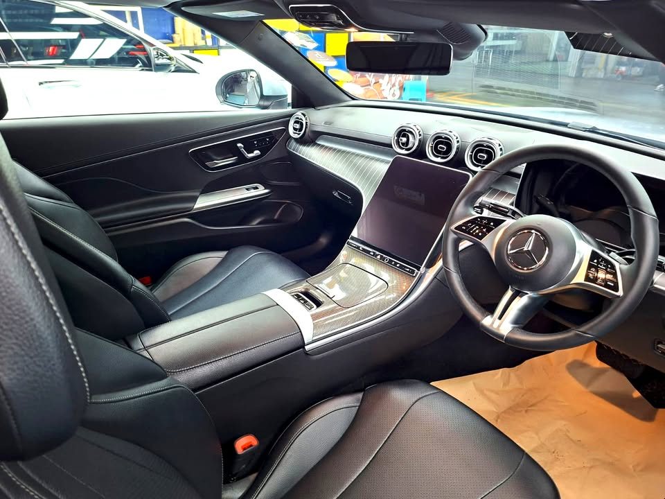 Cabin with black leather seats, steering wheel and portrait centre screen.