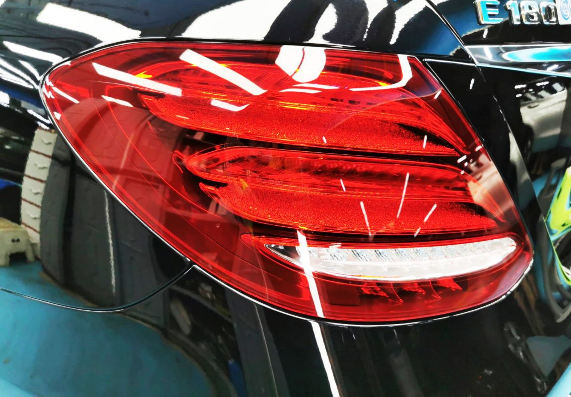 The coated bonnet of the Mercedes-Benz E180 under workshop lighting.