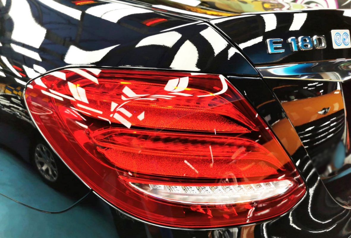 The coated bonnet of the Mercedes-Benz E180 under workshop lighting.