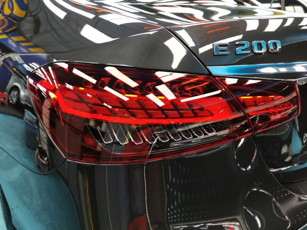 The coated bonnet of the E200 AMG under workshop lighting.