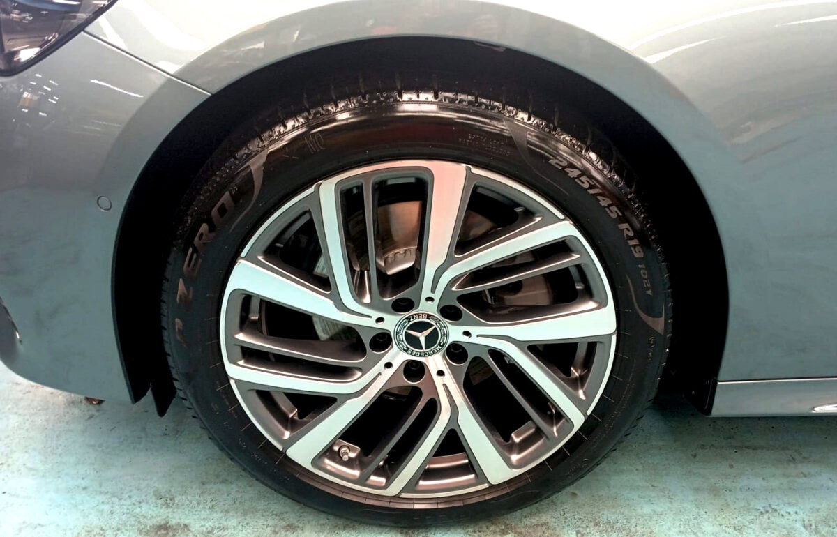 The coated bonnet of the Mercedes-Benz E200 under workshop lighting.