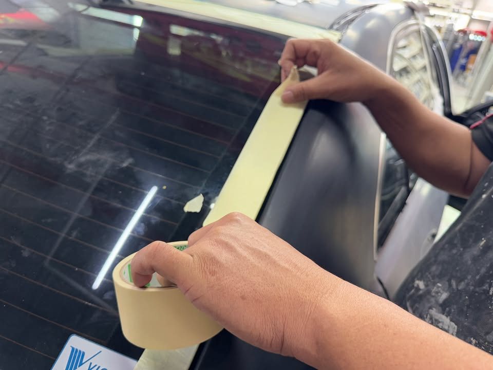 Masking tape being run along the rear window glass.