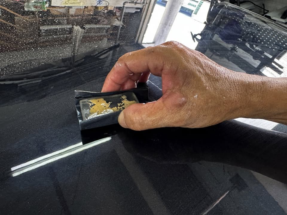 A hand sanding the freshly painted black bonnet with a sanding block.