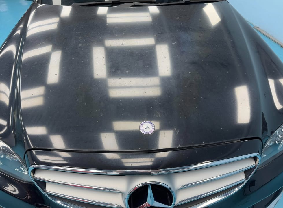 The black bonnet and grille with workshop lights reflected in the paint.