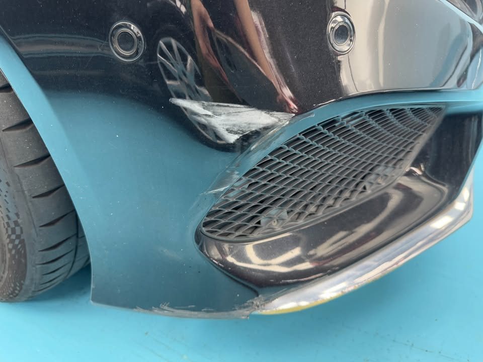 Close-up of the front bumper air intake and grille mesh on the black paint.