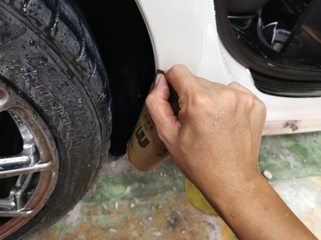 Wet-sanding the E200's panels to smooth the existing paintwork.