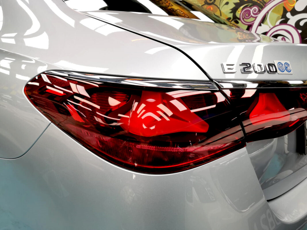 The coated bonnet of the Mercedes-Benz E200 under workshop lighting.