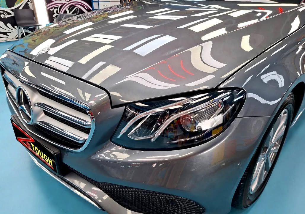Front of the grey Mercedes-Benz E200 showing the grille, three-pointed star and left headlamp.