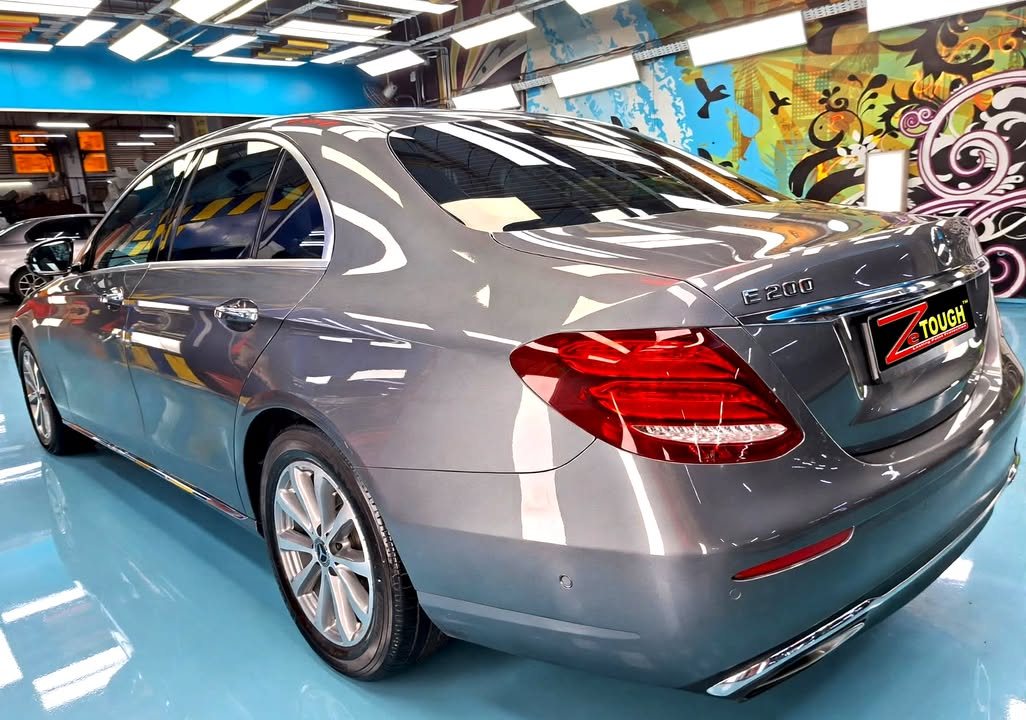 Rear three-quarter view of the grey Mercedes-Benz E200 in the workshop.