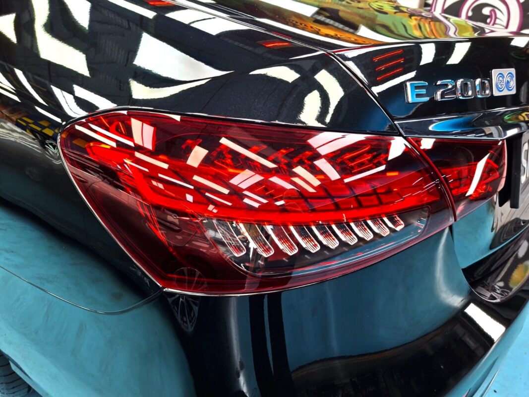 The coated bonnet of the Mercedes-Benz E200 under workshop lighting.