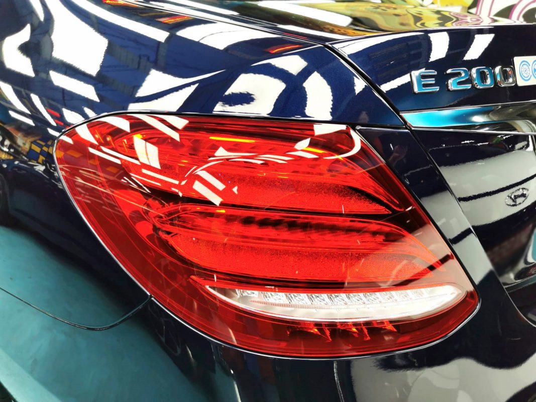 Close-up of a coated body panel reflecting the workshop.