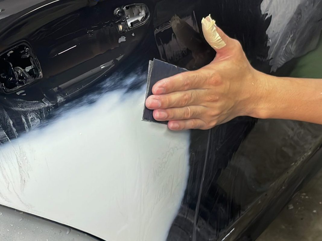 Wet-sanding the E220d's panels to smooth the existing paintwork.