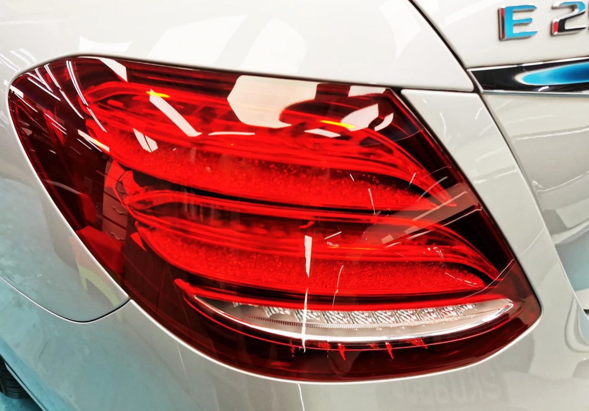 The coated bonnet of the Mercedes-Benz E250 under workshop lighting.