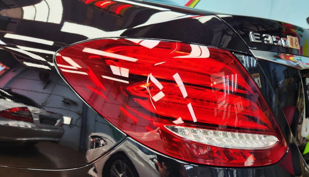 Close-up of a coated body panel reflecting the workshop.