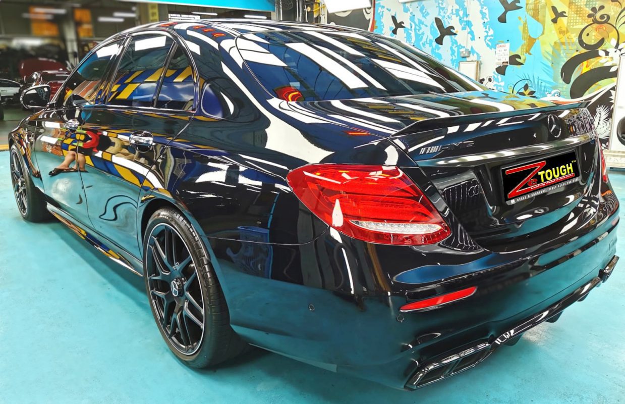 Close-up of a coated body panel reflecting the workshop.