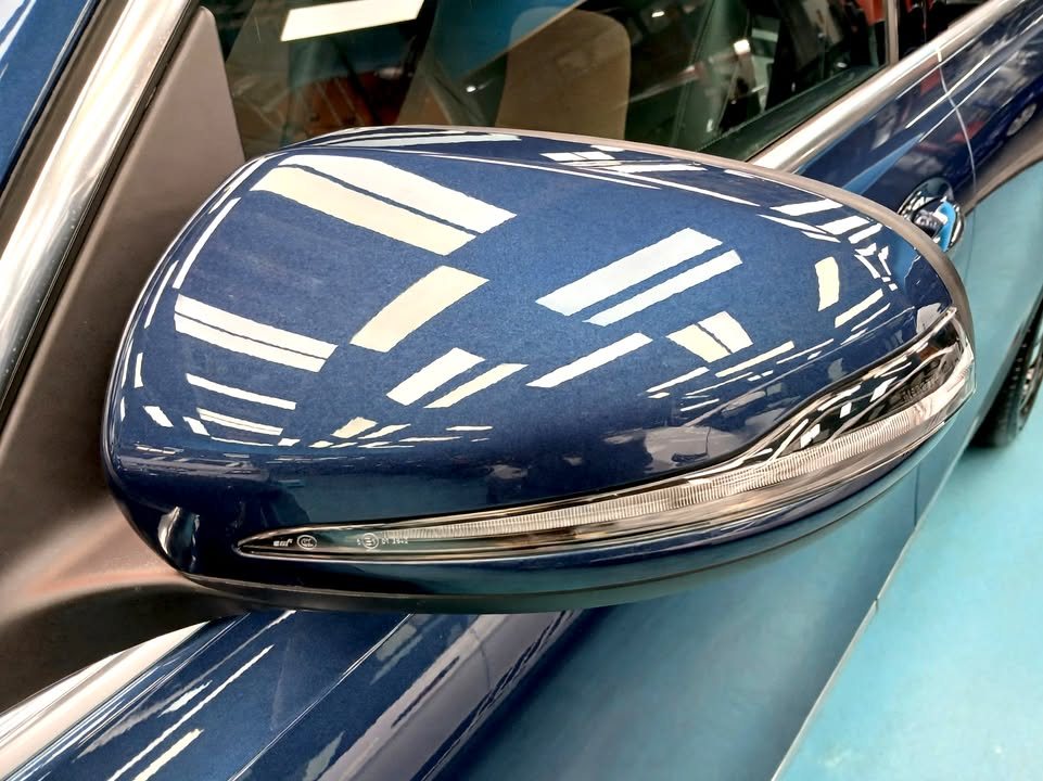 Blue wing mirror cap on the Mercedes-Benz EQB reflecting the workshop lights.